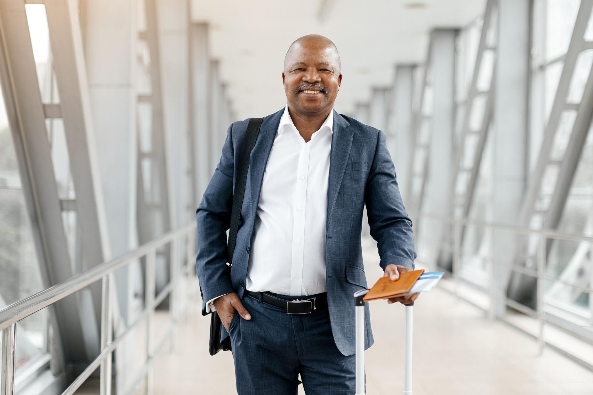 Business traveller walking through an airport terminal with luggage and travel documents